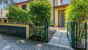 A residential building with a tiled roof, a yellow facade, and a green gate. - Nice apartment for 4 guests with pool, A/C, WIFI, TV, terrace and panoramic view (Riparbella)