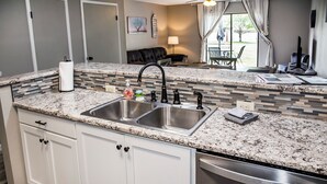 A kitchen with a granite countertop, stainless steel sink, and dishwasher.