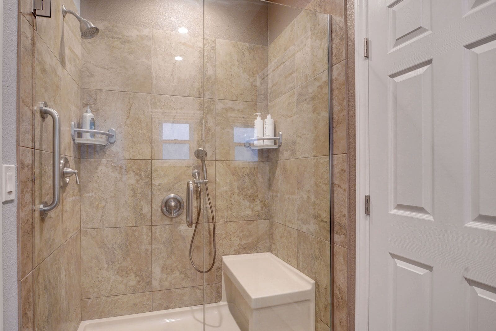 A modern bathroom with a walk-in shower, grab bars, and a toilet.