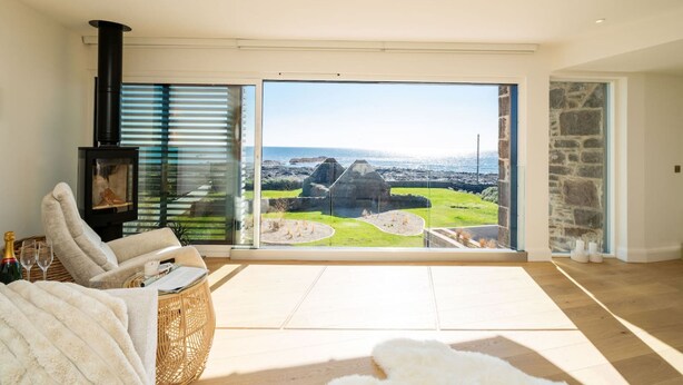 Een ruime woonkamer met een grote glazen deur die leidt naar een balkon met een prachtig uitzicht.