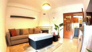 A modern living room with a sofa, a coffee table, a fireplace, and a large plant. - Lisbon, modern T2 with balcony in Barcarena (Oeiras)