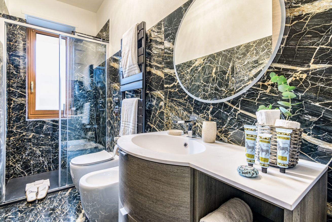 A modern bathroom with a curved vanity, a glass shower enclosure, and a large mirror.