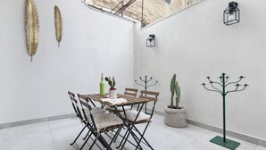 A small, open-plan living space with a dining table, chairs, a potted cactus, and a coat rack. - La Galla House | Lecce Selection (Lecce)