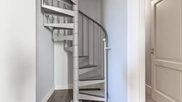 Eine weiße Wendeltreppe mit Geländer und einer Tür am Fuß.