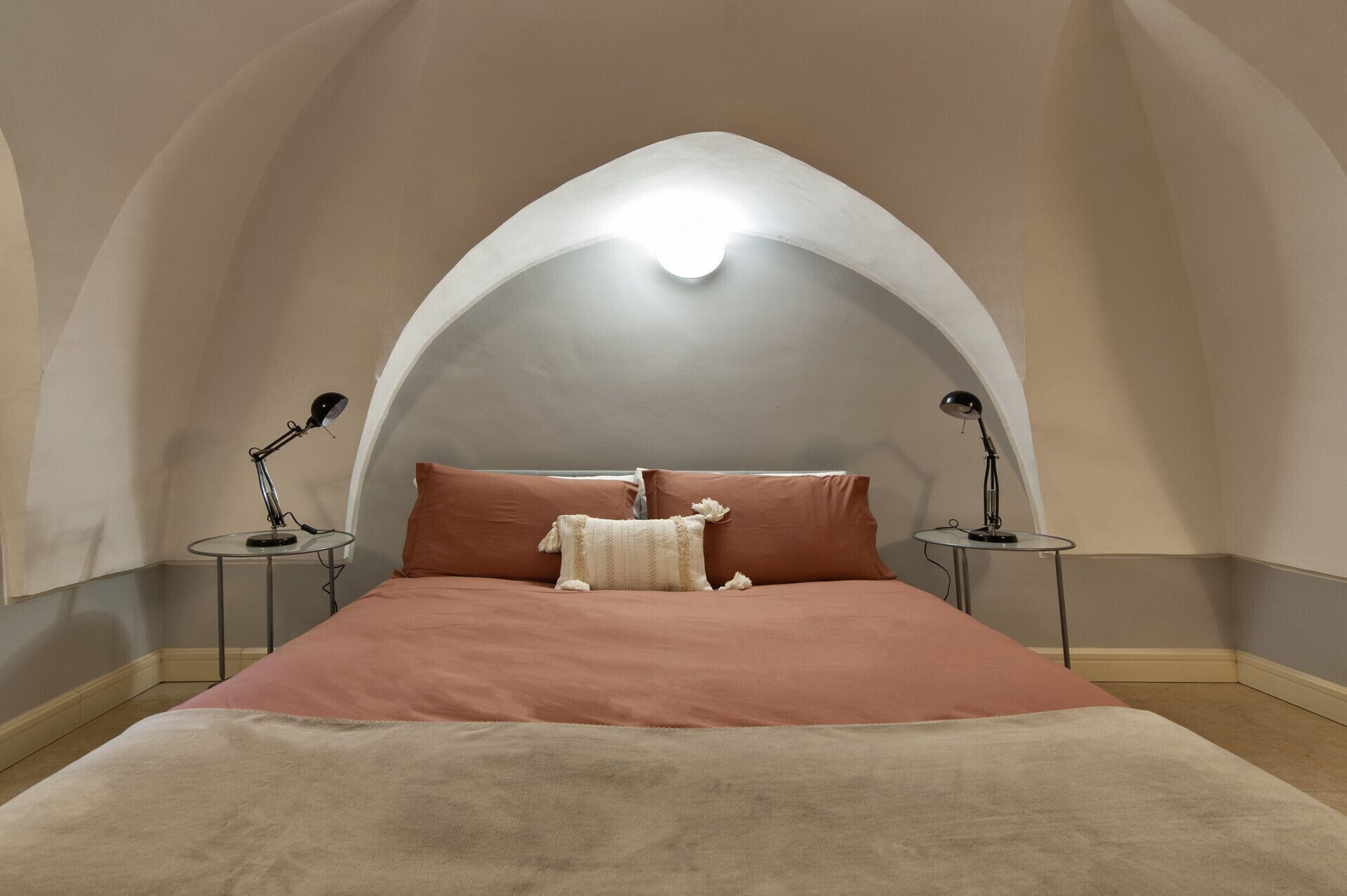 Ein Schlafzimmer mit einem Bett, zwei Nachttischen und einer Lampe auf jedem Tisch.