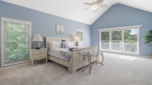 A bedroom with a bed, bedside tables, a ceiling fan, and large windows. - Lakefront Escape on Lake Sinclair • Hot Tub • Ideal for Families & Friends (Eatonton)