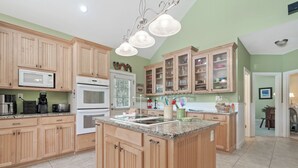 A kitchen with wooden cabinets, a granite countertop, a built-in oven, and a microwave. - Lakefront Escape on Lake Sinclair • Hot Tub • Ideal for Families & Friends (Eatonton)