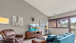 Ein Wohnzimmer mit einer Ledersofa, einem blauen Sofa, einem Fernseher auf einem Holzboden und Kunstwerken an den Wänden.