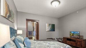 Ein Schlafzimmer mit einem Bett, einem Fernseher, einer Holzkommode und einem Bild an der Wand.