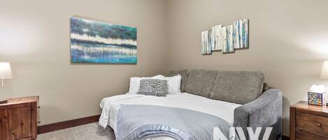 A bedroom with a bed, two nightstands, a wooden dresser, and artwork on the walls.