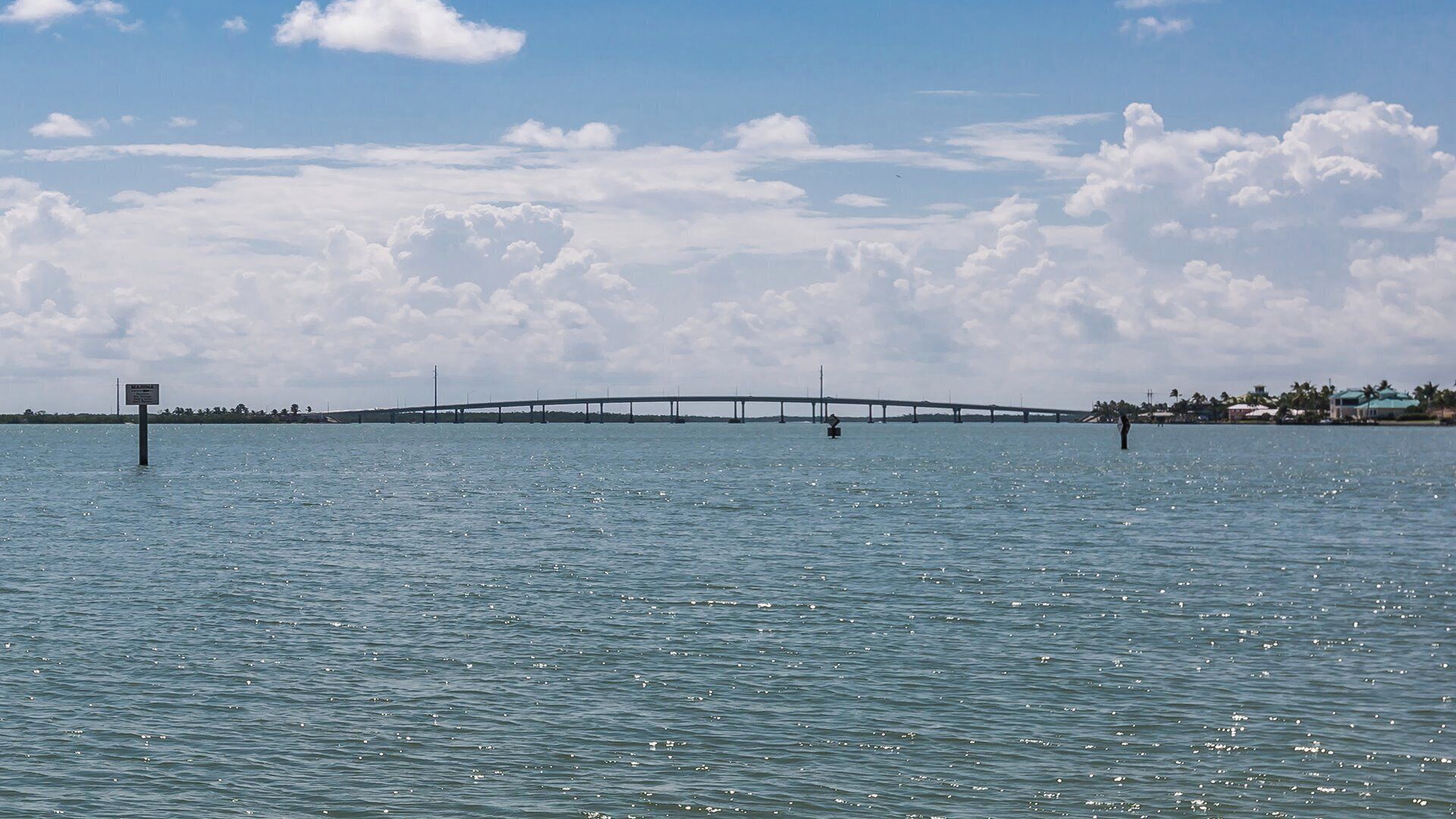 A bridge over a body of water with a clear sky and clouds.