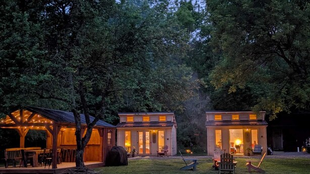 A rustic cabin with a covered patio and a small outdoor seating area.
