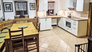 Une cuisine chaleureuse avec des meubles blancs, une table à manger en bois et un four encastré.