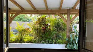 Ein Zimmer mit Holzbalkendecke, einem Fenster mit Gartenblick und einer Zeitschrift auf dem Boden.