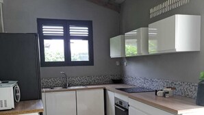 Eine moderne Küche mit weißen Schränken, einem eingebauten Backofen und einem Fenster mit Jalousien.