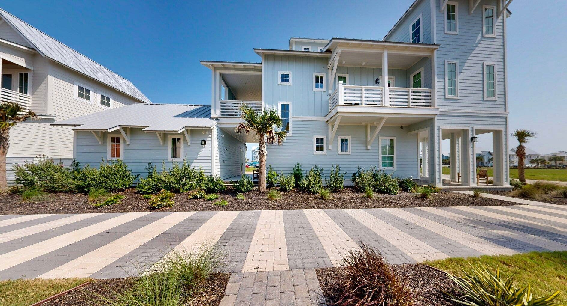 A two-story residential building with a covered porch and a landscaped front yard.