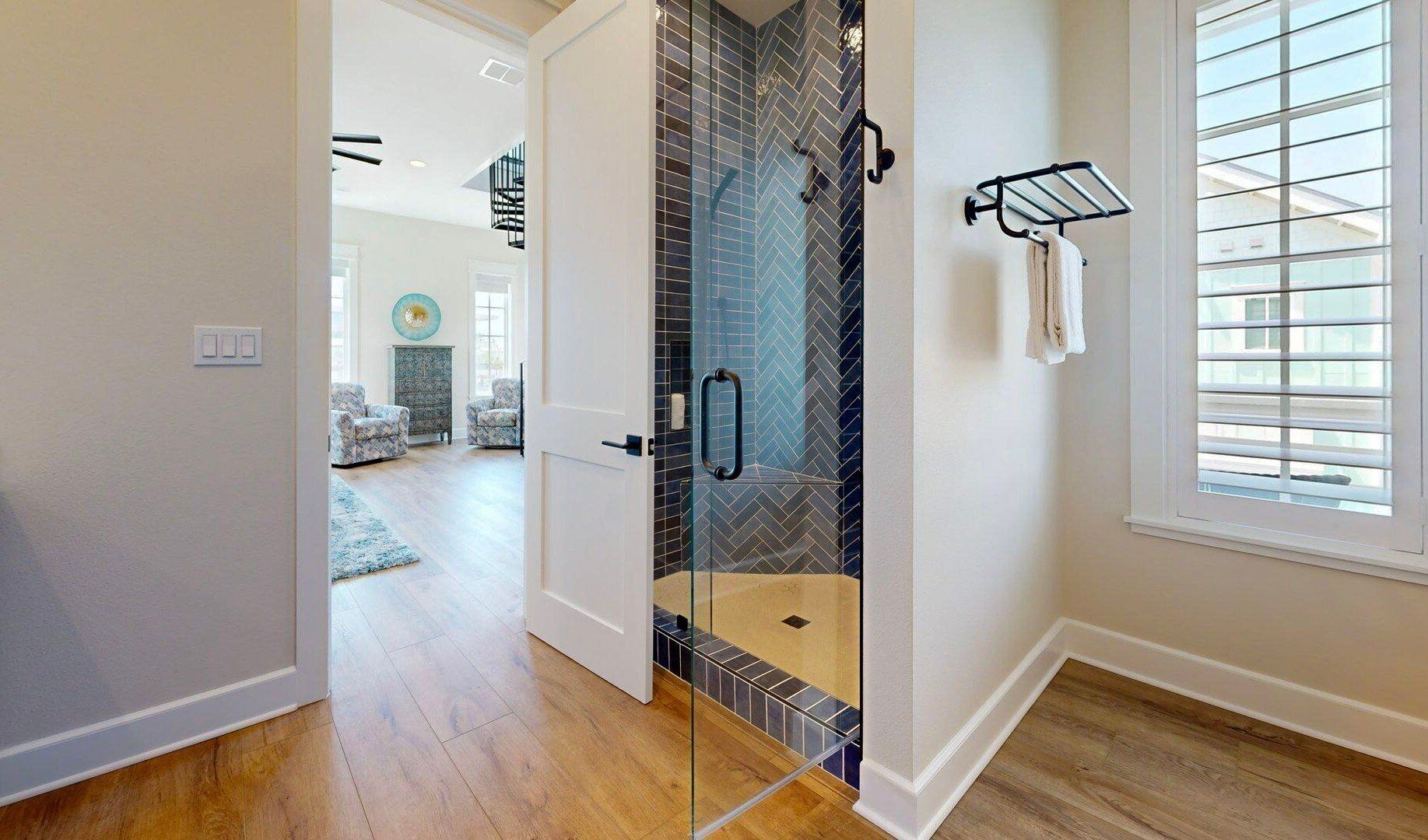 A modern bathroom with a glass shower enclosure, a bathtub, and a window with blinds.