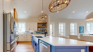 A modern kitchen with a large island, stainless steel appliances, and pendant lighting. - Shared Resort Style Pools, Boardwalk to the Beach, Beautiful Views (Port Aransas)