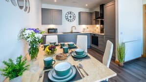 A modern kitchen with grey cabinets, a microwave, and a clock on the wall.