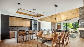 A modern kitchen with wooden cabinets, a central island, and a dining area with a large wooden table and chairs. - The Timberline @ Spring Brook Resort (Wisconsin Dells)