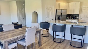 A modern kitchen with white cabinets, a stainless steel refrigerator, and a granite countertop.