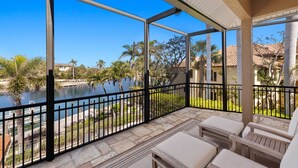 A balcony with a view of a body of water, palm trees, and a building in the background. - Spectacular Direct access canal front beauty! (Sanibell)
