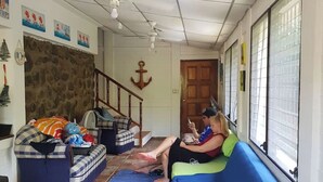 Een woonkamer met een blauwe bank, een stenen muur en een houten trap.