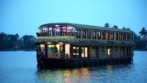 A houseboat with a two-story structure, a balcony on the upper level, and a water-facing front entrance. - Marvelous Boathouse (Alappuzha)