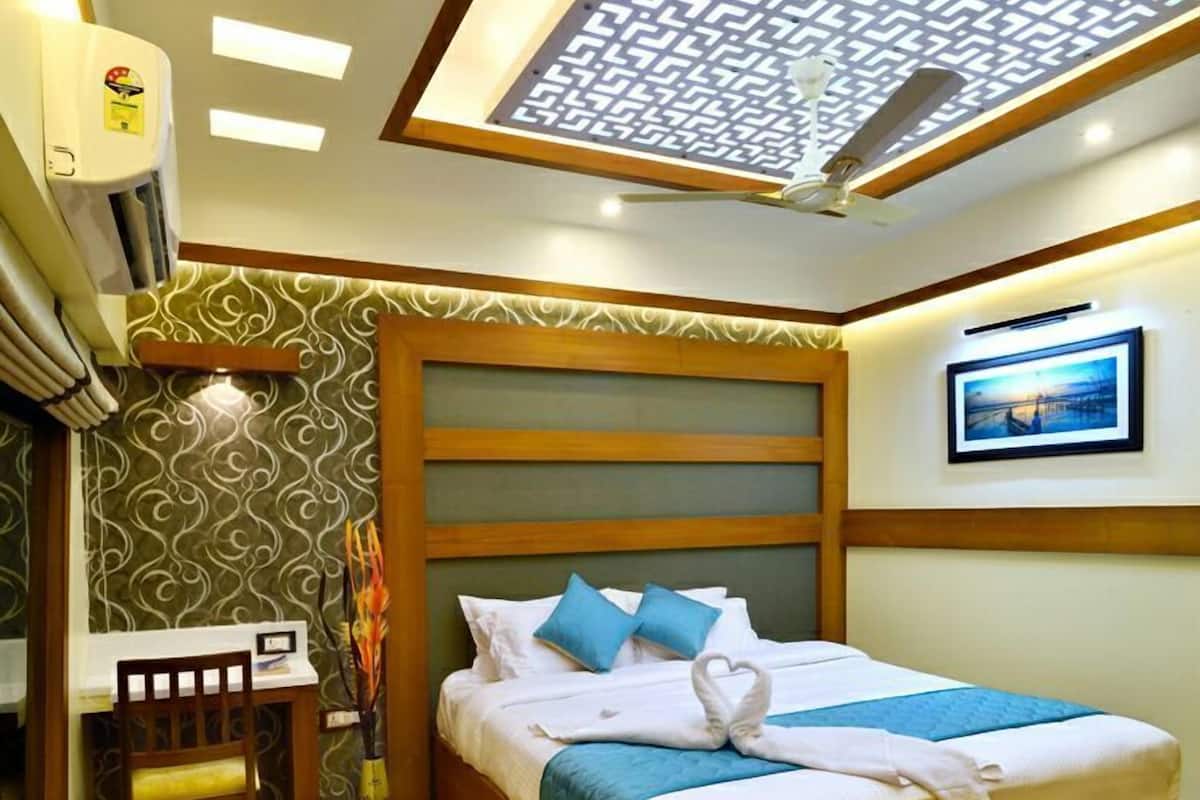 Habitación de hotel con cama, escritorio y silla. Cuenta con un ventilador de techo y un equipo de aire acondicionado.