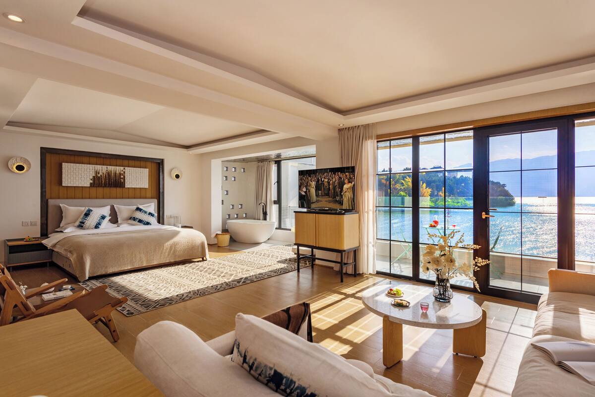 Un dormitorio amplio con una cama grande, una zona de estar con una mesita de centro y vistas al mar.