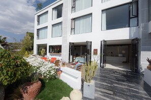 A modern two-story building with large windows, a well-maintained garden with various plants and flowers, and a seating area with outdoor furniture. - Shuanglang 7 Fun sea Hotel (Dali)