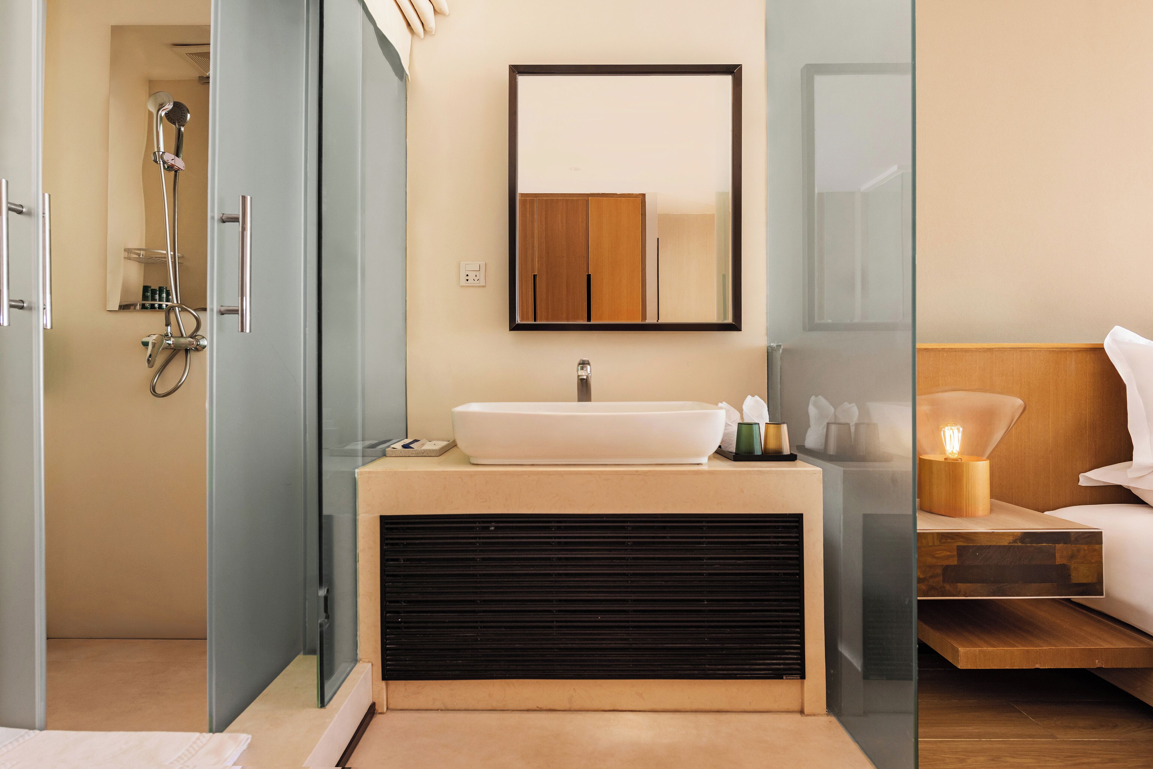 A modern bathroom with a glass-enclosed shower, a white sink, and a wooden cabinet above it.