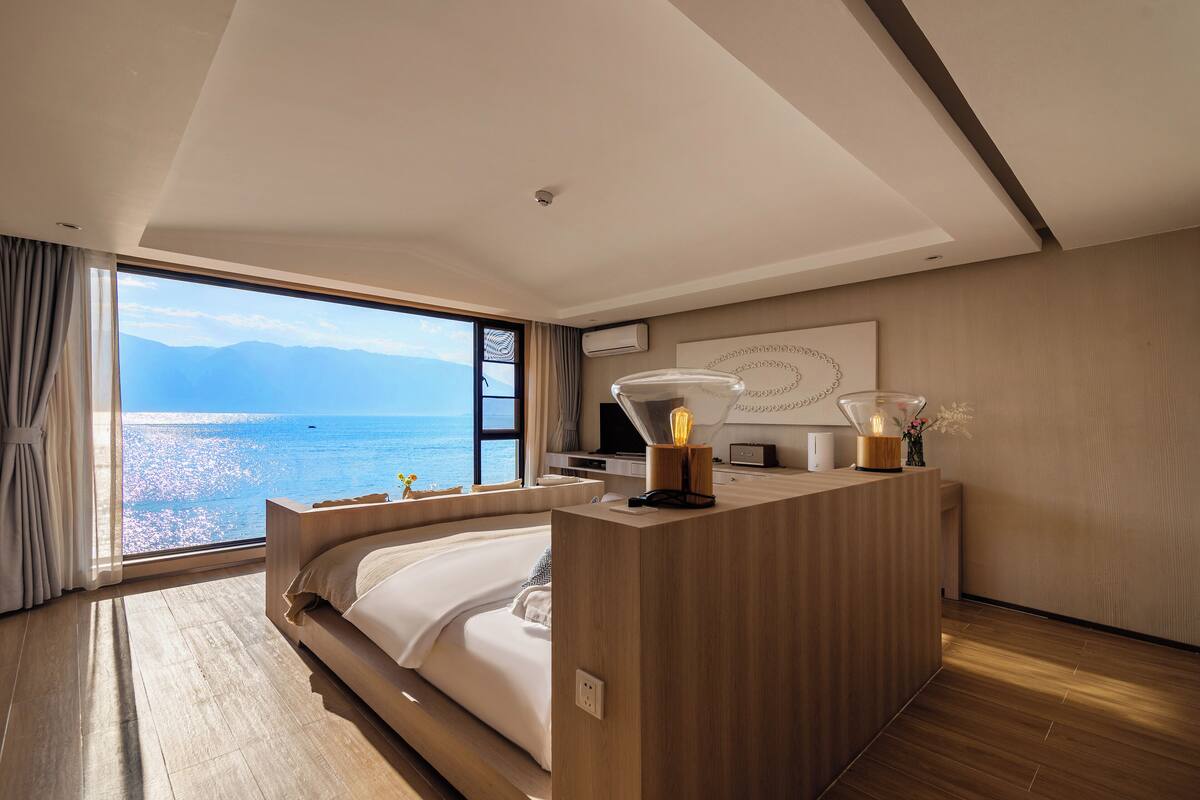 Un dormitorio moderno con una cama grande, un escritorio de madera y vista al mar.