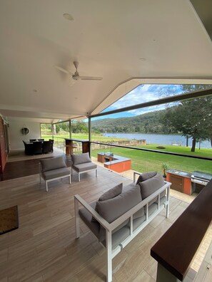 Um pátio amplo com vista para um lago, um ventilador de teto e mobiliário de exterior.