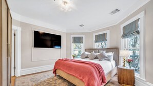A bedroom with a bed, a television mounted on the wall, and a window with a view of trees. - Estate room at bed & breakfast in downtown Napa with AC, WiFi, pool, and hot tub (Napa)