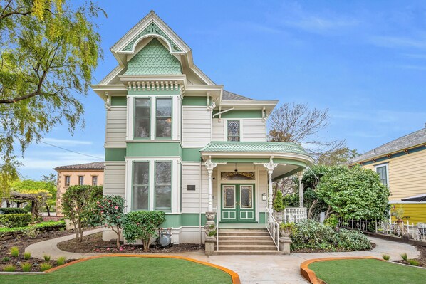 A two-story Victorian-style house with a green and white facade, a front porch, and a well-maintained garden. - Estate room at bed & breakfast in downtown Napa with AC, WiFi, pool, and hot tub (Napa)