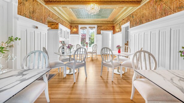 A dining area with white paneled walls, a wooden floor, and a chandelier. - Estate room at bed & breakfast in downtown Napa with AC, WiFi, pool, and hot tub (Napa)