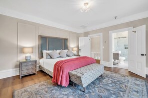 A bedroom with a bed, bedside tables, a bench, a patterned rug, and a bathroom visible through an open door. - Estate room at bed & breakfast in downtown Napa with AC, WiFi, pool, and hot tub (Napa)