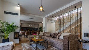 Una sala de estar moderna con un sofá, una mesa de centro y una escalera con una pared de piedra.