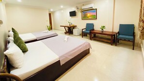 Quarto de hotel com duas camas, uma escrivaninha, duas cadeiras, uma TV e um quadro na parede.