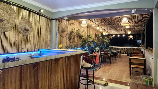 Uma área de bar com piscina, paredes de madeira e luminárias penduradas.