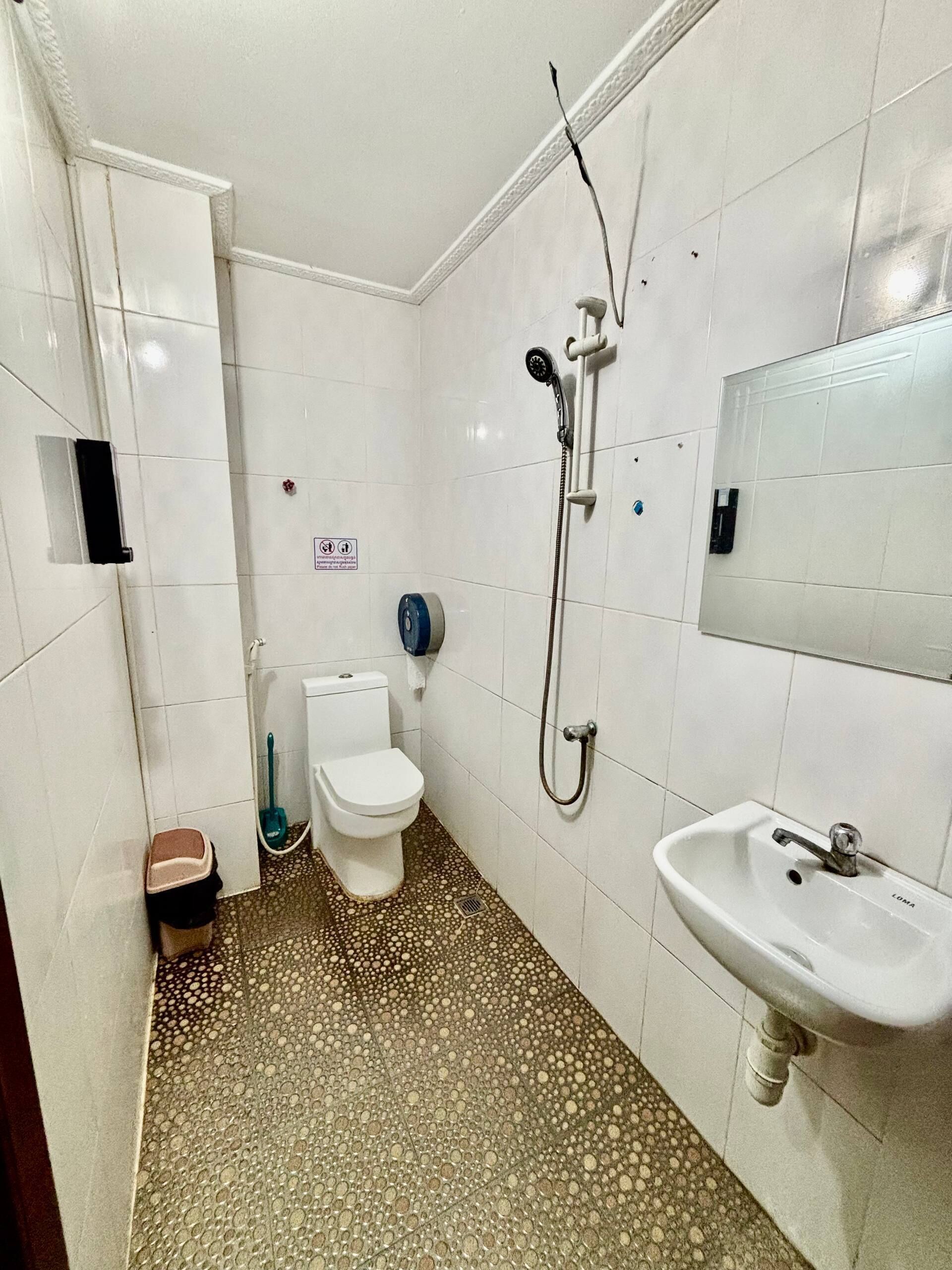 A bathroom with a toilet, a shower, and a sink.