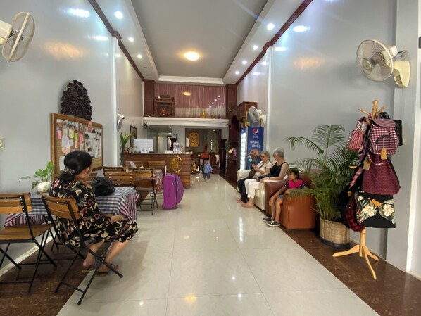 Un vestíbulo de hotel con zonas de estar, un mostrador de recepción y una exhibición de maletas.