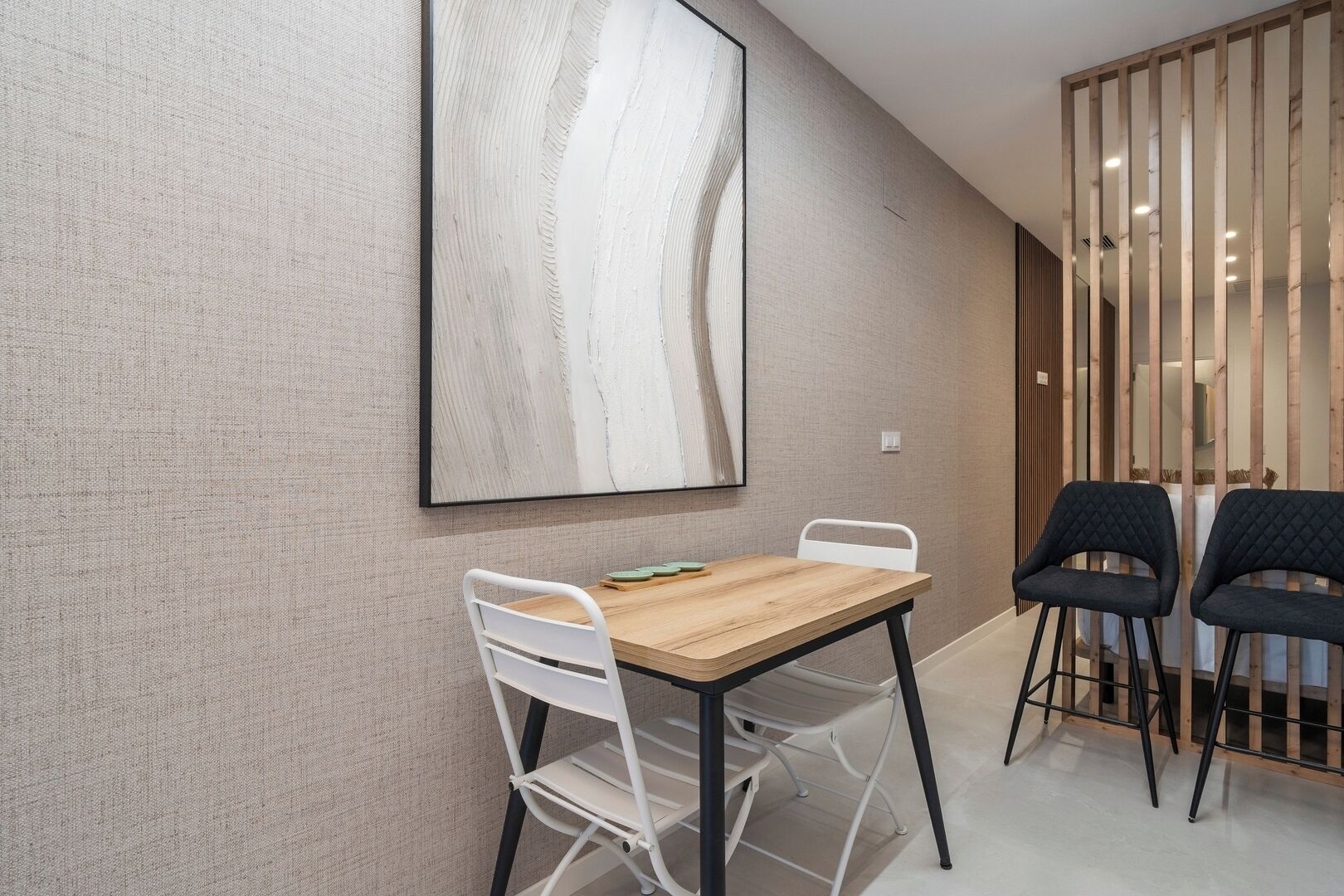 Een moderne eetruimte met een houten tafel, witte stoelen en een groot abstract schilderij aan de muur.