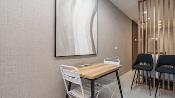 Een moderne eetruimte met een houten tafel, witte stoelen en een groot abstract schilderij aan de muur.