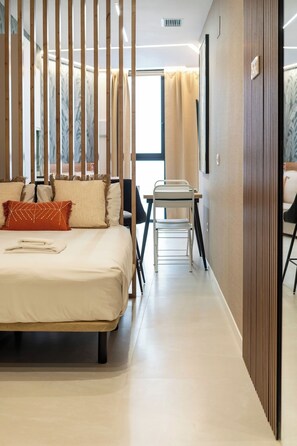 Ett modernt hotellrum med en säng, ett litet bord och en stol.