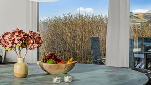 Un comedor moderno con una mesa redonda, un jarrón de flores y un frutero.