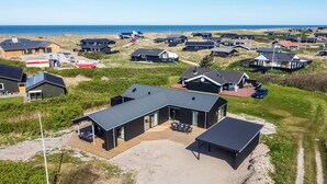Una casa moderna con una terraza amplia y un porche cubierto, enclavada en un paisaje costero.