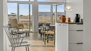 Una cocina moderna con ventanas amplias, un comedor con sillas y vistas al exterior.