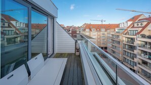 A modern apartment with large windows, a balcony, and a view of neighboring buildings. - Apartment on Belgian Coast Near Beaches (Knokke-Heist)